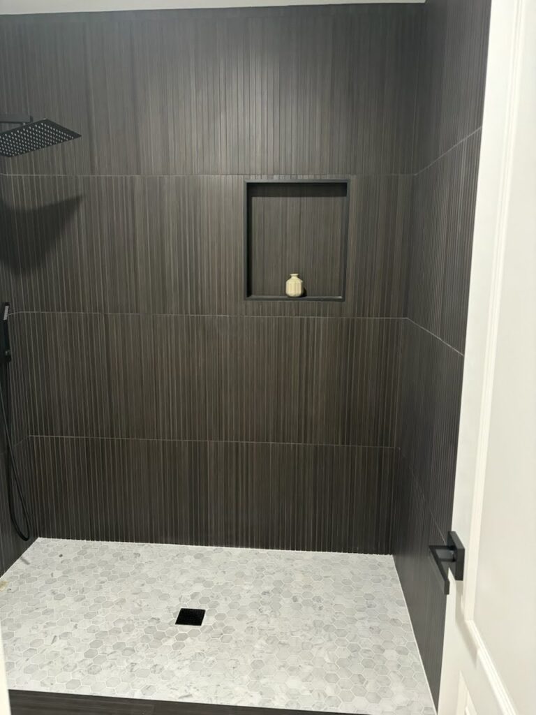 Modern walk-in shower with glass enclosure, subway tile walls, rainfall showerhead, and built-in niche – elegant and functional bathroom design